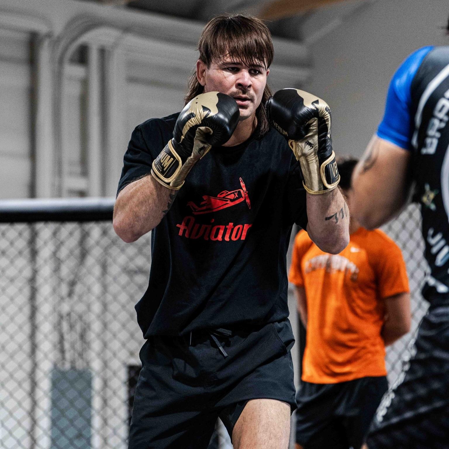 Diego Lopes treinando de luvas douradas, com camiseta do Aviator